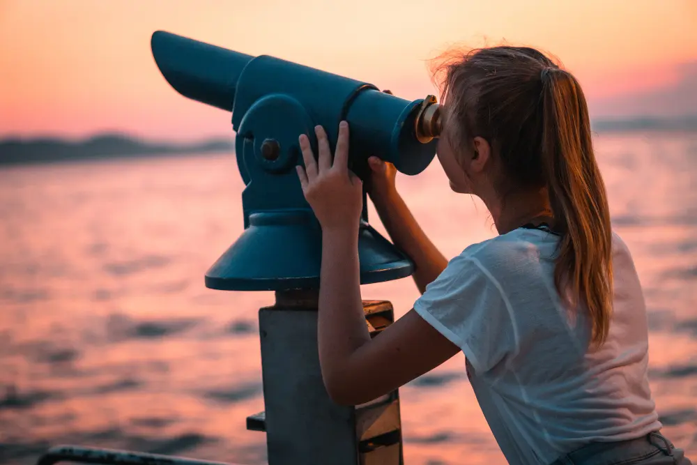 A girl watching a beautiful sight through a telescope
